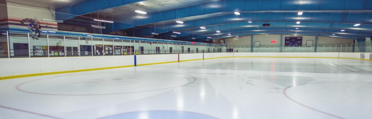 an indoor ice rink with smooth ice and no one on it yet