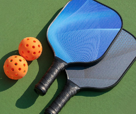 image of 2 pickleball paddles and balls on a court