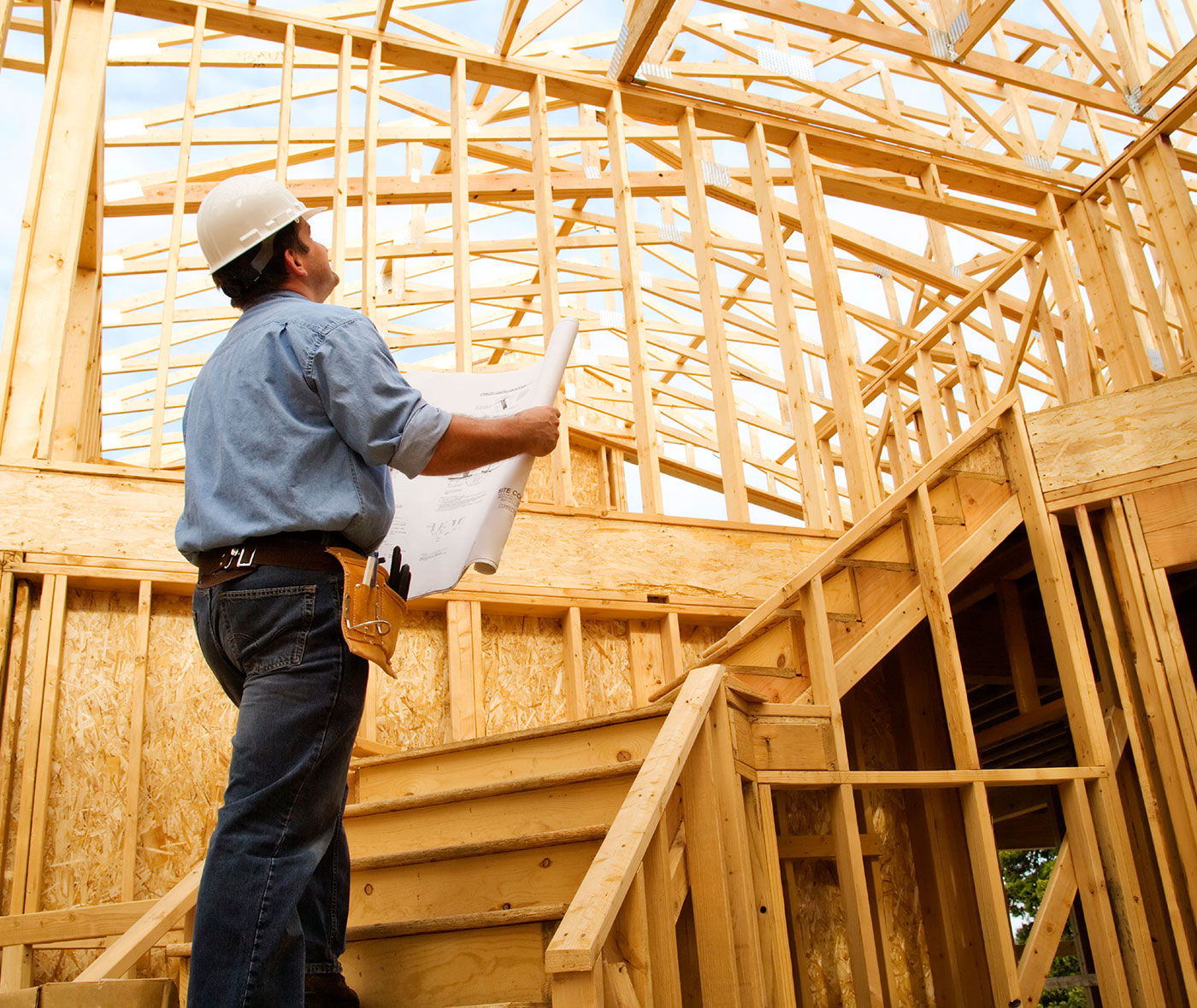 Contractor reviewing construction plans in wood framed house