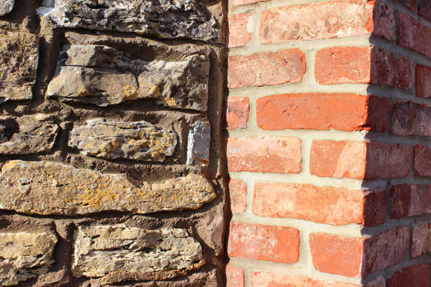 Red-brick gate post, contrasting with an adjacent old cobblestone wall that has been repaired and repointed