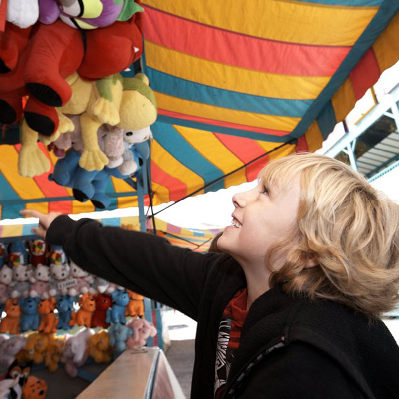 Young boy playing games at the midway at a fall fair/festival
