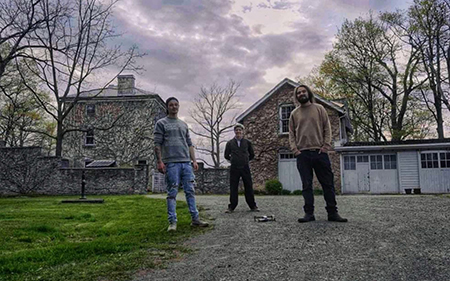 3 people standing together in front of an old stone building