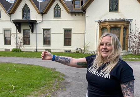 Woman standing in front of building showing matching tattoo on arm