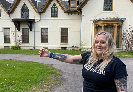 Woman standing in front of building showing matching tattoo on arm