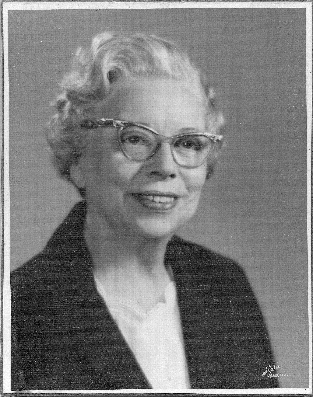 Anne Foster. Older woman with short hair in glasses, smiling.