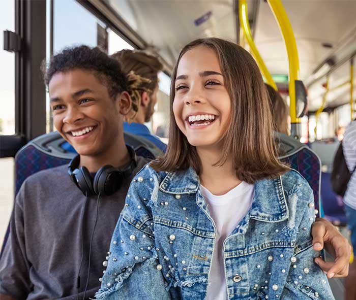Two teenagers riding the bus smiling