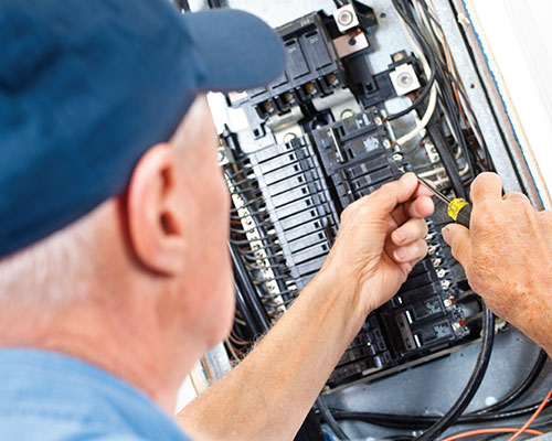 Man working on breaker panel in house.