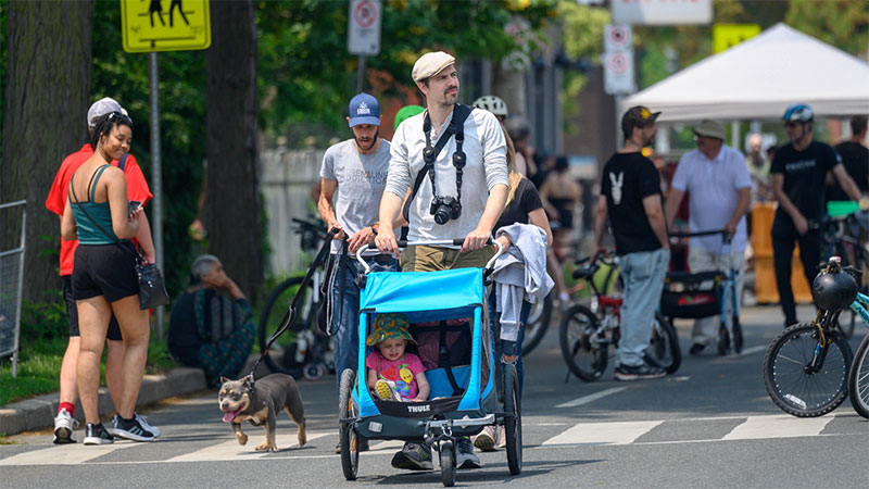 A man pushes a stroller in a crowd of people on King Street during Open Streets 2023