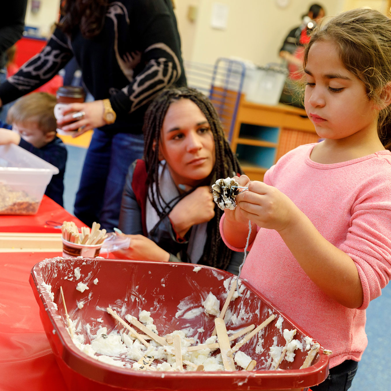 Young female child making a craft with pinecones, glue and birdseed