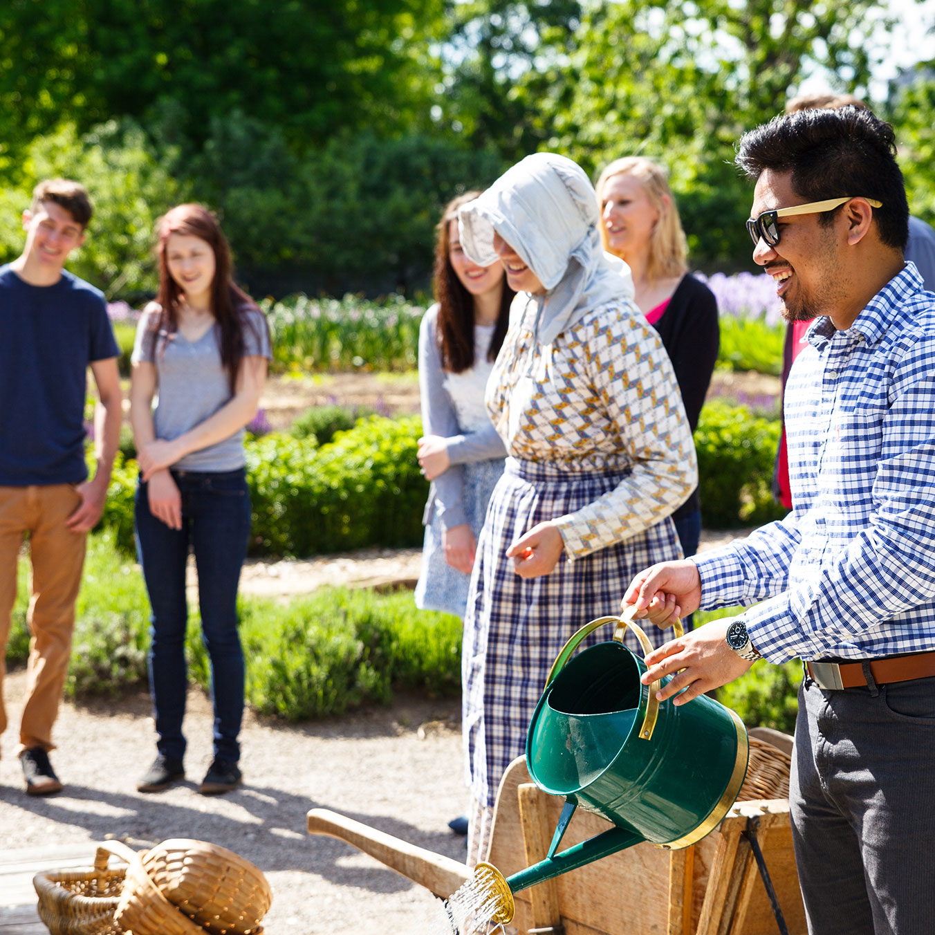 A group of people watering flowers in Historic Garden at Dundurn