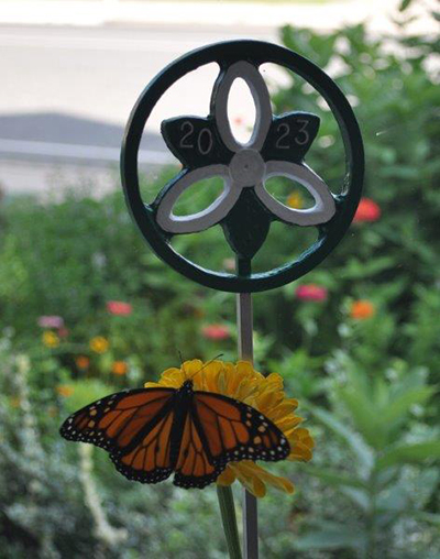 Trillium Awards statue in a garden with a monarch butterfly landing on a flower in front