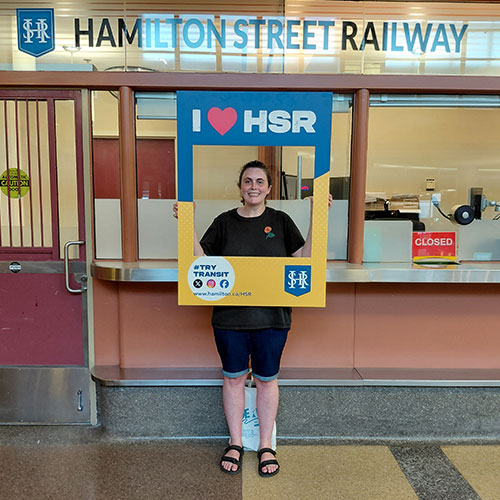 HSR’s Track Your Trip Study winner Emma posing with I Love HSR sign