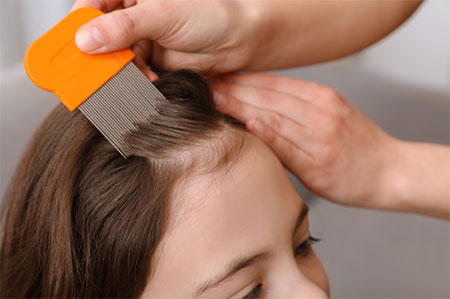 Close up of hands using a lice comb on a child's hair