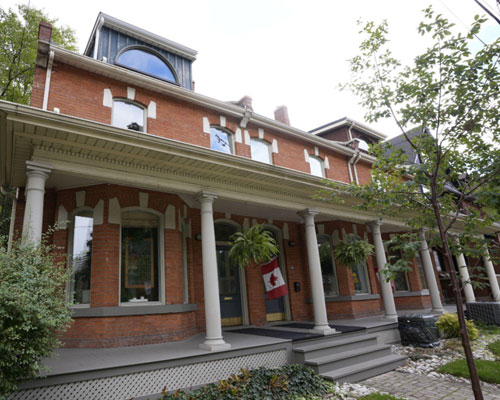 Victorian brick rowhouse with continuous veranda, bay windows and brick/stone lintels