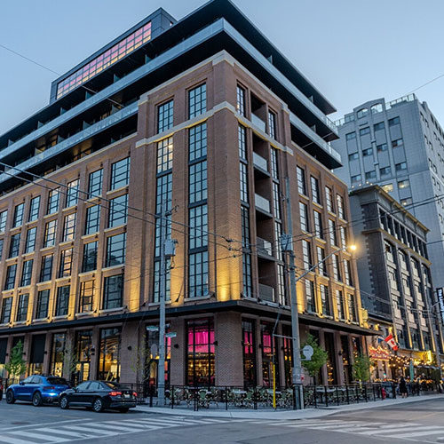 9 storey brick building with expansion windows with various sized rental units and grade flour restaurant.