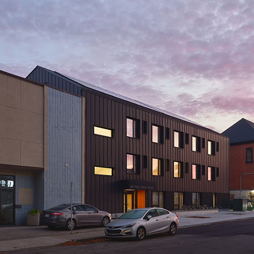 Modular construction 3 level building with large windows with generous landscaping and resident space