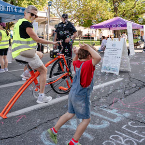 A person on a bike smiles at a child dancing in a cloud of bubbles on King Street during Open Streets Hamilton