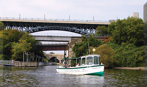 The Hamiltonian boat tour in the water, passing under a bridge