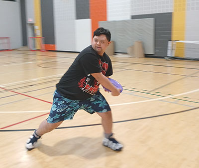 Child playing frisbee in a recreation centre indoor gym