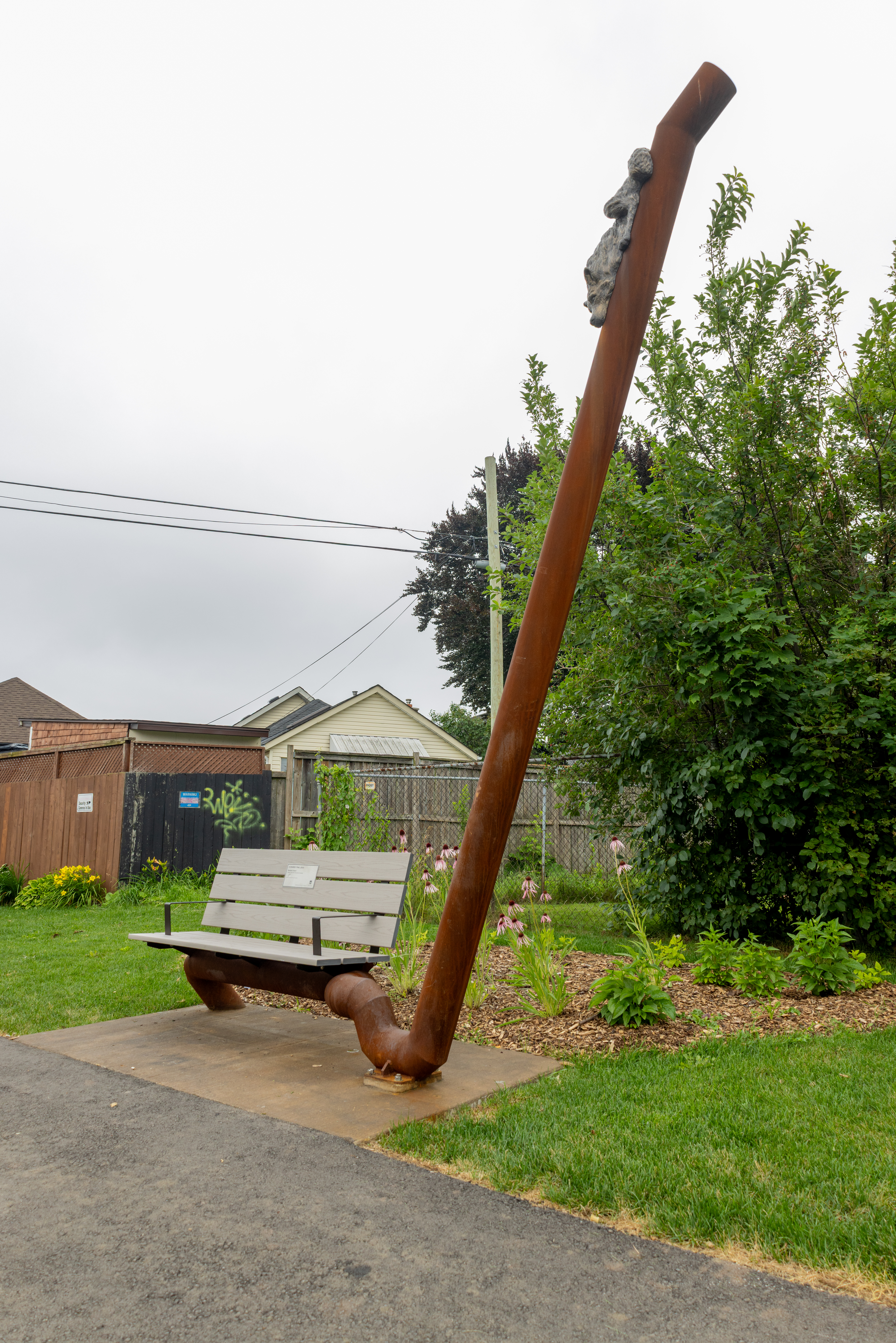 Sculpture: Park bench with pole with animal sculptures placed on it  - "A Shared Trail" by Brandon Vickerd
