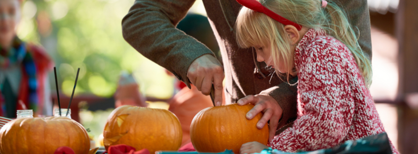 Adult and young girl carving pumpkins