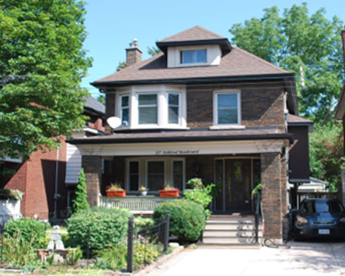 Two storey brown brick home with covered porch