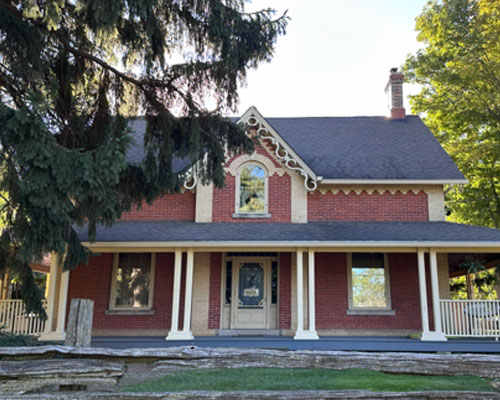 Two storey red brick farmhouse with wraparound porch