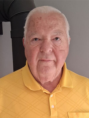 Man with grey hair and a yellow collard shirt