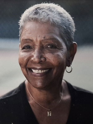 Woman with brown skin and grey hair smiling