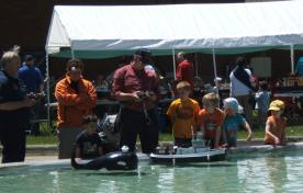 people playing with remote control boats in a pool