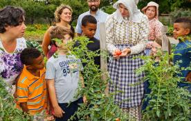 group of children and adults in a garden with a tour guide in period clothing