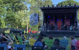 Outdoor concert stage, live performance with people sitting in lawn chairs