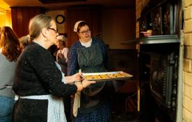 Cook demonstrator putting a tray of cookies in the oven during cooking workshop