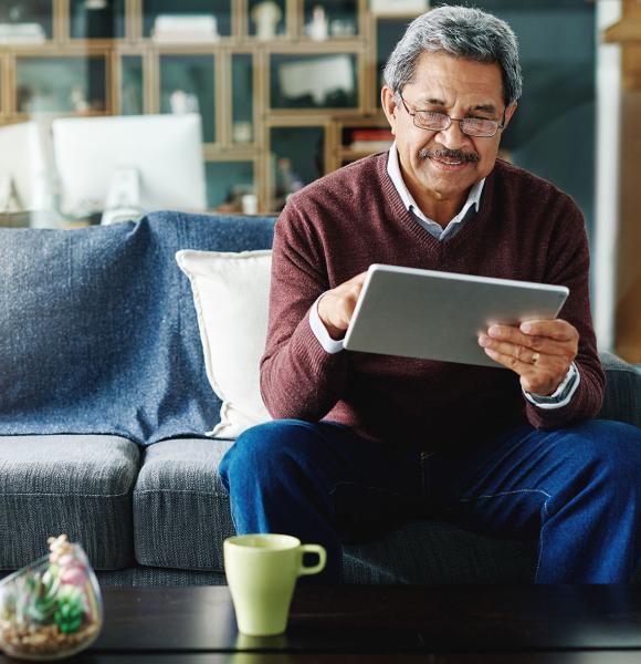 Cropped shot of a mature man using his digital tablet while relaxing at home.