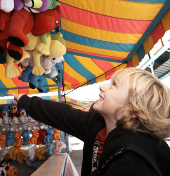 Young boy playing games at the midway at a fall fair/festival