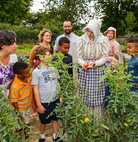 group of children and adults in a garden with a tour guide in period clothing