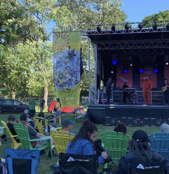 Outdoor concert stage, live performance with people sitting in lawn chairs