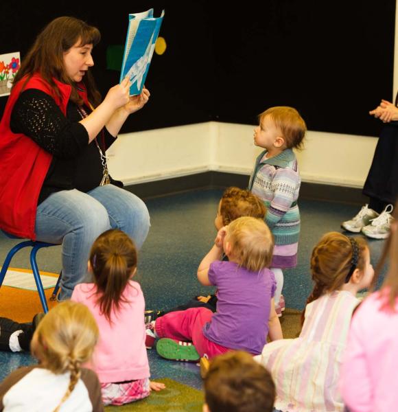 children sitting around an adult reading a story
