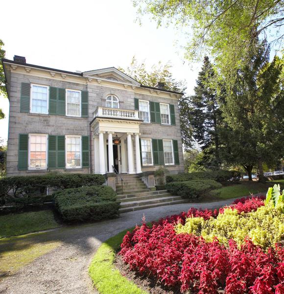 Exterior of Whitehern a 2 storey grey brick building with front porch and circular drive