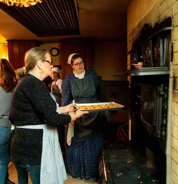 Cook demonstrator putting a tray of cookies in the oven during cooking workshop