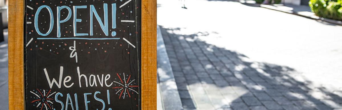 Sidewalk sign outside business near walkable street