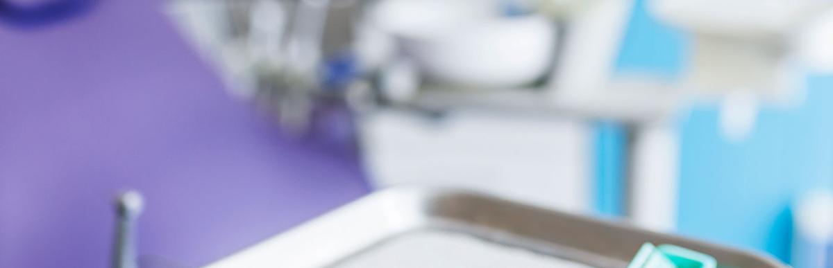 Close-up image of dentist tools and dentist's chair in the background.