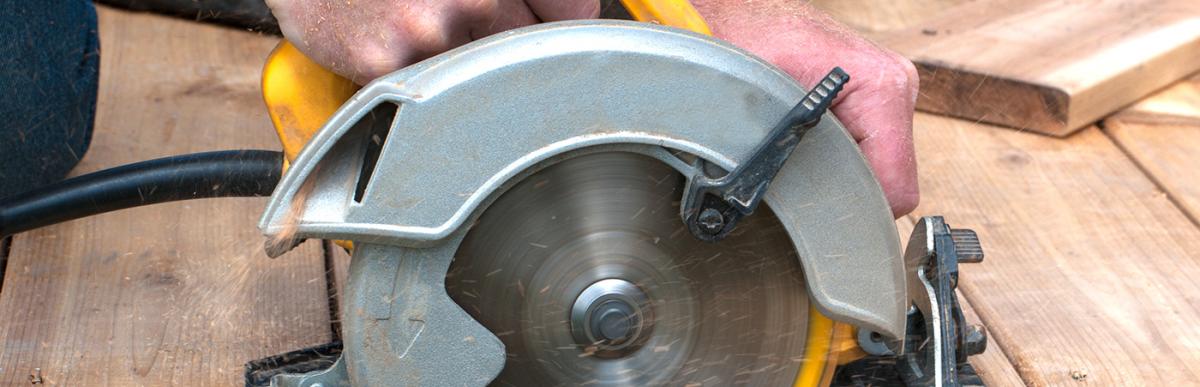 Person cutting boards with circular saw at edge of deck construction