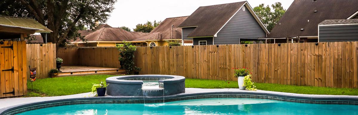 Inground swimming pool in backyard with surrounding fence in neighbourhood
