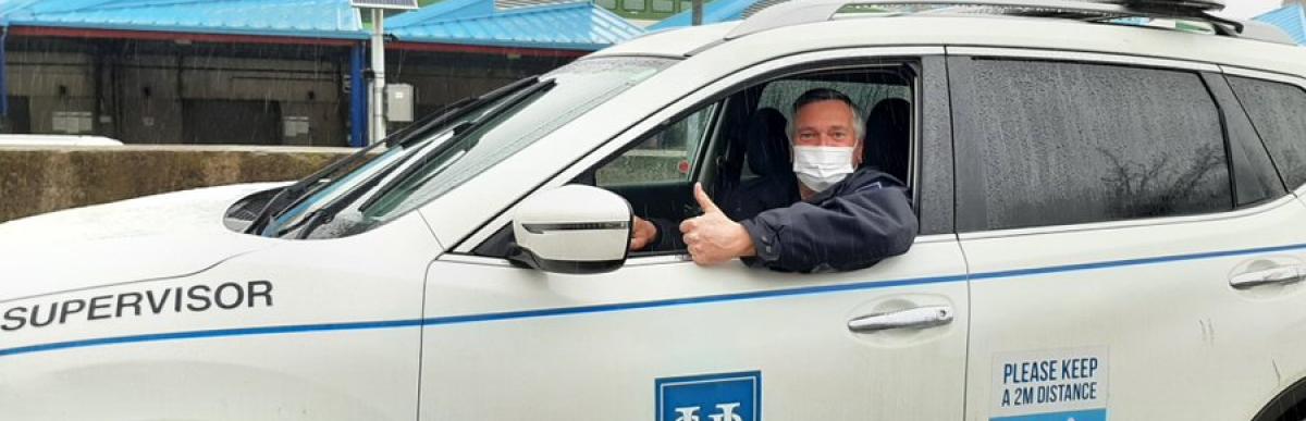 Man wearing a medical mask, driving an HSR supervisor vehicle and giving the thumbs up.
