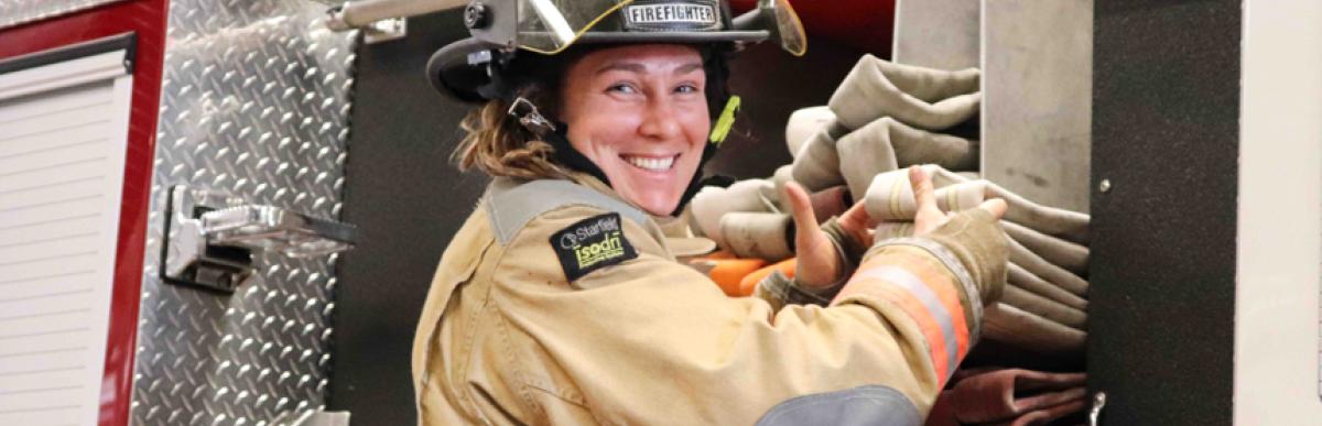 Firefighter packing fire hose on truck