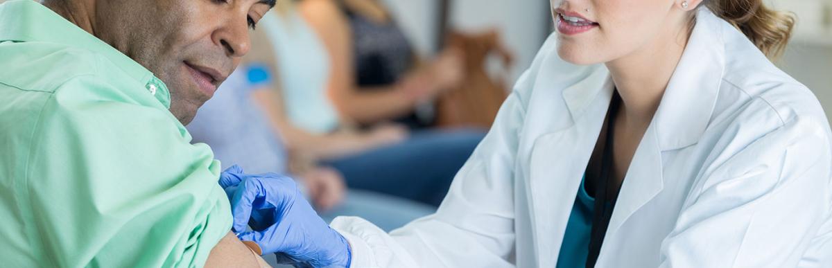 Female healthcare professional gently places a bandage on a mature male patient's arm. 