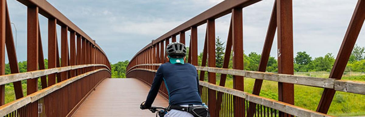 Man biking on bridge over highway.