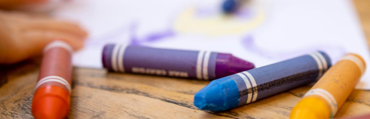 child with crayons and paper on a table