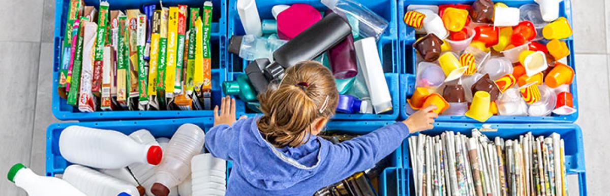 child sorting recycling into different recycling bins